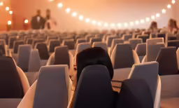 a woman with long dark hair sitting in an empty auditorium