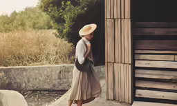 a woman with a hat walks by water