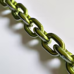 a metal chain linked to another link on white surface