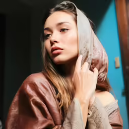 a woman standing in front of a mirror wearing a blanket