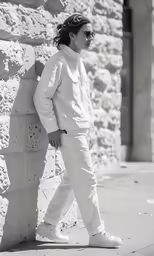 a woman walking down a sidewalk next to a stone wall