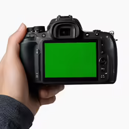 man holding up a camera with a green screen