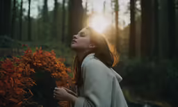 a woman looking up at the sun in the woods