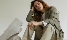 a young lady is sitting on the ground with her hands on her head