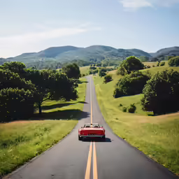 the car is driving down the road in front of the mountains