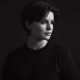 a woman with short hair and black dress looking back