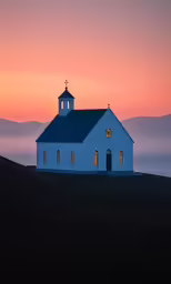a small church in a field at sunset