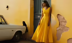 a woman in a yellow dress by a white car