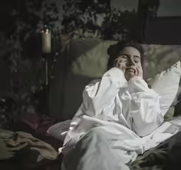 a woman dressed in a long white robe is laying on a bed