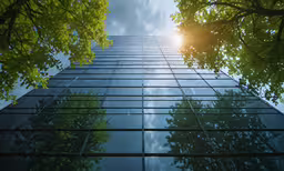 a large skyscraper with trees and sun shining in between them