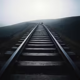 a lone train track sitting in the middle of a grassy hill
