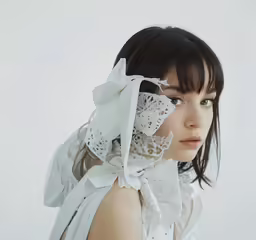 a woman wearing a white dress has a ribbon around her neck