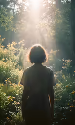 a young person walking towards the sun through some trees