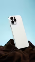 a white smart phone sitting on top of brown blanket