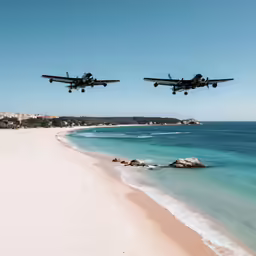 two planes are flying low over the ocean and sandy beach