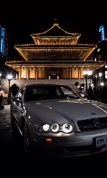 an automobile parked in front of a building with lights around it