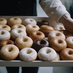 someone putting a doughnut in a large box