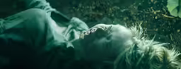 a young woman laying in the rain with her face half covered