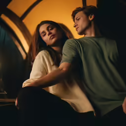 man and woman sitting on wooden bench next to a fireplace