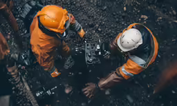 two men in safety gear holding metal object