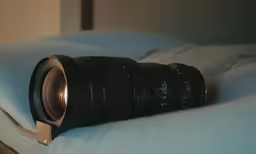 a canon camera lens is sitting on the edge of a bed