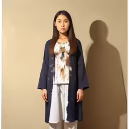 a girl with brown hair wearing a dark coat and white pants