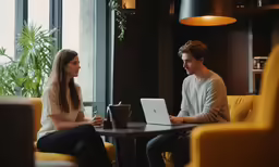 a man and woman sitting together using laptops