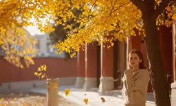 a woman is standing near a tree in the fall