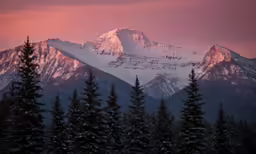 the snow capped mountain peaks are silhouetted against the sky