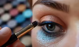 a person with eyeliner that is holding a brush in their hand