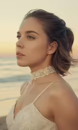 a woman standing on the beach wearing a white dress
