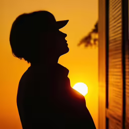 a person standing in front of the sun with a hat on