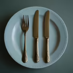 a knife, fork and spoon on a white plate