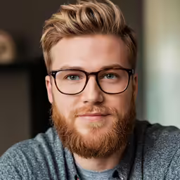 a bearded man with glasses on wearing a sweater