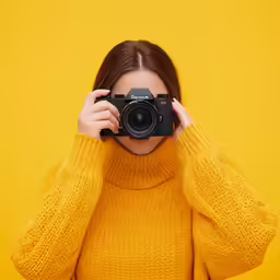 a woman in yellow holding up her camera