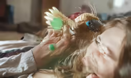 a close up of a girl playing with a toy bird