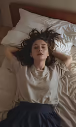 a woman lays in bed with her hair down