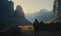 person standing on a mountain trail looking towards mountains