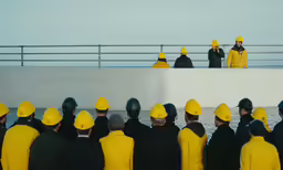 the group is wearing yellow hats and standing in front of a row of people