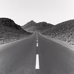 the road in the middle of nowhere with mountains behind it