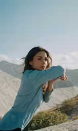 woman standing in the desert doing yoga with mountains behind