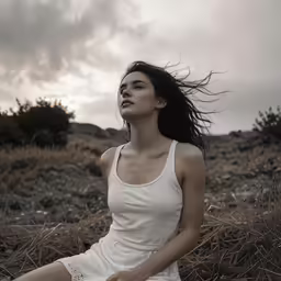 a woman is sitting on a rocky hill