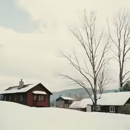 a farm with a snow covered hillside and two houses