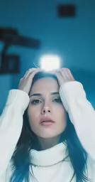 a woman holding her head with one hand and looking off to the side with a flash light above her