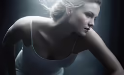 a woman with white tank top posing on the dark background
