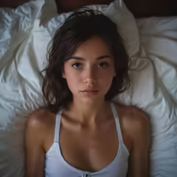 a woman laying on a bed with white sheets