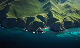 an aerial view of green mountains and water