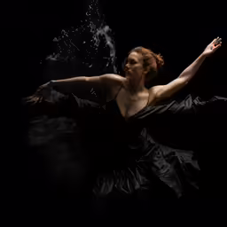 a woman in the water holding a black umbrella
