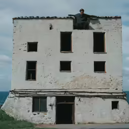 a man in a green shirt standing on the windows of a building