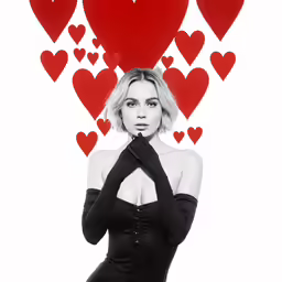 a woman wearing black is standing near many hearts